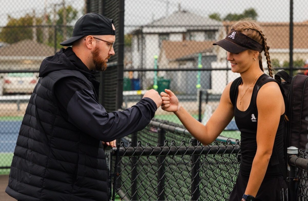 Taylor Loux fist bumping Samanta Romanyuk, a varsity tennis player. Photo taken by Lisa Garrett.